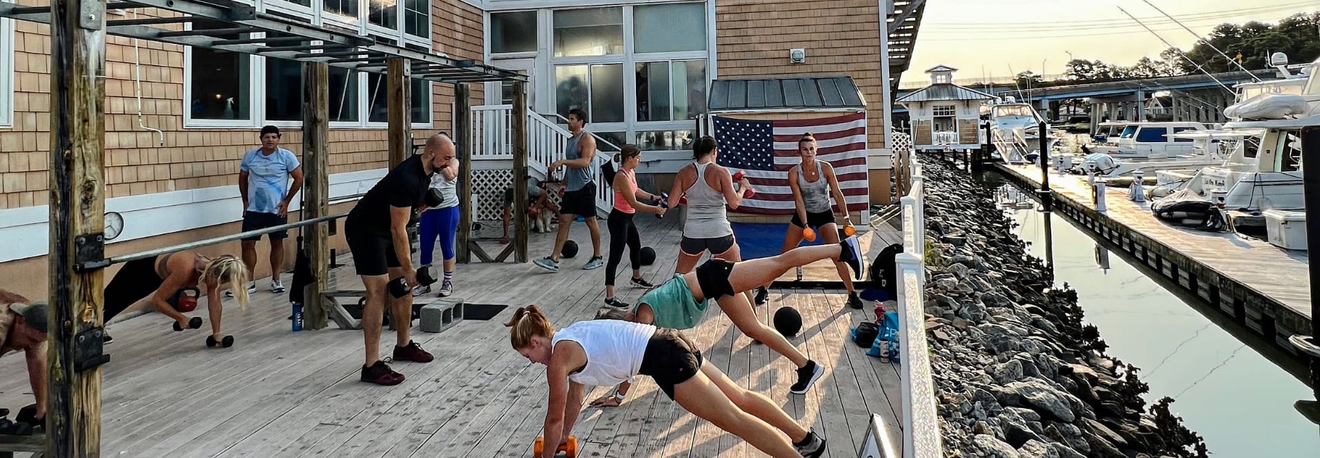 gym members use dumb bells during a group exercise class on the back deck at inlet fitness in virginia beach