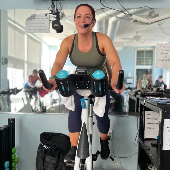 a spinning studio class instructor rides on a stationary bike while instructing the class at inlet fitness