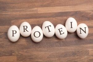 Wood background with eggs displaying the word protein.